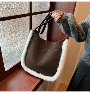 Detail of vintage suede handbag featuring white faux fur trim and circular button accent