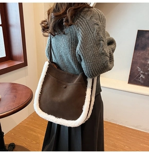 Close-up of brown faux suede bucket bag with white plush trim worn by a model