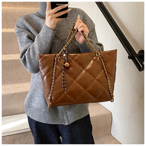 Macro shot of the brown quilted tote bag with gold chain strap and metal pendant charm