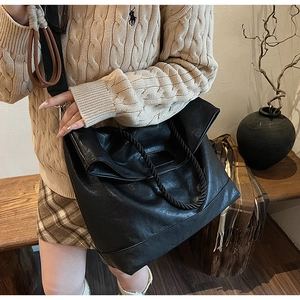 Détail du grand sac cabas en cuir noir avec poignée tressée et bandoulière amovible
