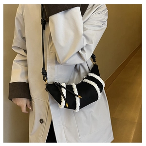 Model wearing a black crescent shoulder bag with white faux fur trim and grey coat