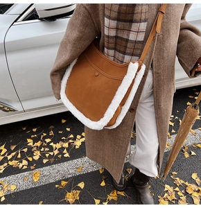 Detail of suede bucket bag with faux fur trim shown on a model in autumn street setting