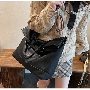 Détail du sac fourre-tout noir avec anses en corde et bandoulière large sur mannequin