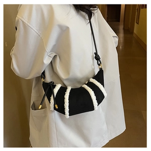 Close-up of crescent bag with black suede texture and white fuzzy stripes on model
