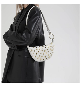 Détail du sac à selle demi-lune blanc avec rivets dorés et fine bandoulière