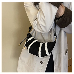 Detail of plush拼接 croissant bag featuring white faux fur stripes and gold hardware accents