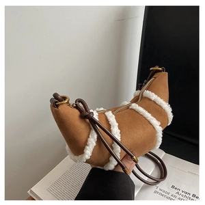Detail of plush faux shearling trim on a brown suede crescent bag with gold zipper