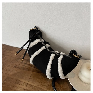 Detail of plush faux fur trim and silver zipper on black crescent crossbody bag