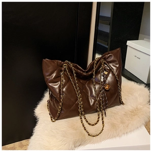 Detailed close-up of dark brown quilted tote bag with golden chain strap and ball charm