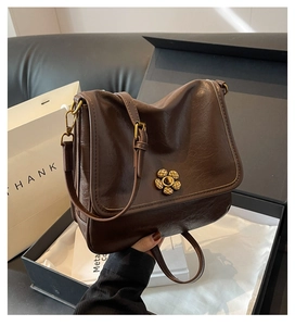 Detail of vintage brown leather bag with golden floral buckle in a premium gift box set