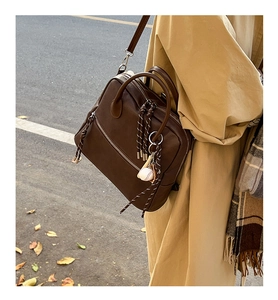 Dettaglio borsa vintage marrone con tiretto intrecciato e ciondolo a forma di baseball