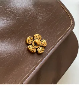 Macro detail of dark brown vintage leather texture and golden flower-shaped hardware buckle