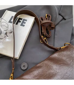 Detail of dark coffee leather tote bag with smooth shoulder strap and vintage hardware