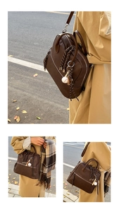 Dettaglio cartella vintage marrone con cerniere metalliche e ciondolo a forma di baseball
