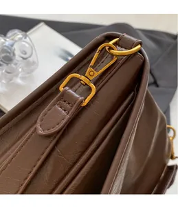 Detail of dark brown leather handbag featuring gold metal hooks and textured stitching