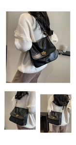 Detail of black pleated faux leather bag with elegant golden flower metal clasp