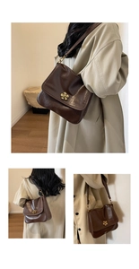Detail of a dark brown leather tote bag featuring a decorative gold flower metal clasp