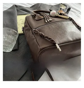 Dettagli dello zaino vintage in pelle marrone con ciondolo da baseball e zip in metallo