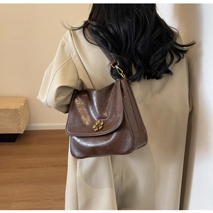 Detail of dark brown vintage shoulder bag featuring a gold flower metal buckle and leather strap
