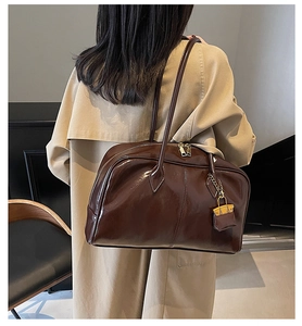 Detail of dark brown glossy PU leather tote bag with a mini decorative charm