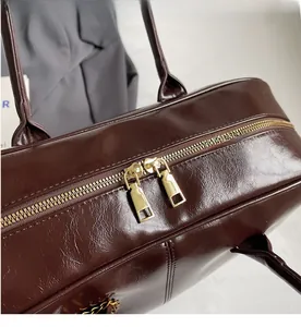 Detail of smooth golden double zippers on a dark brown textured leather handbag