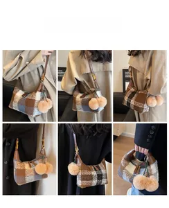 Detailansicht der karierten Wolltasche mit Lederriemen und flauschigen Anhängern