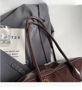 Detailed close-up of dark brown PU leather handbag with durable handle and metal zipper