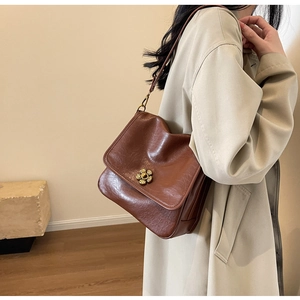 Detail of vintage dark brown faux leather crossbody bag with golden flower metal clasp