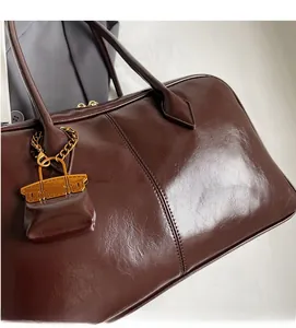 Detail of a chocolate brown patent leather handbag with glossy texture and gold charm