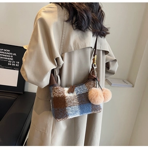 Detail of plush checkered crossbody bag with brown leather strap and fuzzy pompom charms