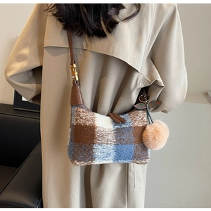 Detail view of a vintage plaid shoulder bag with soft tweed fabric and brown plush pompom charm
