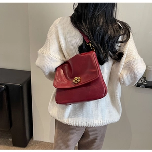 Detailed view of a vintage red leather crossbody bag with a golden floral lock