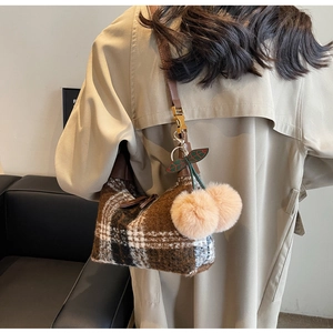 Detailed texture of brown plaid wool handbag with cute pink cherry pompom charm accessory