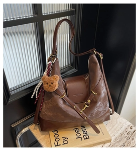 Brown frosted hobo tote bag detail with plush bear charm and striped silk scarf decor