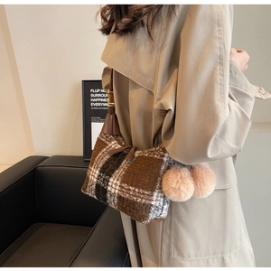 Detail of a brown plaid wool shoulder bag with cute pink plush ball charms