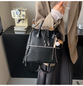 Dettaglio zaino nero in pelle PU con zip argentate e ciondolo a tema baseball sportivo