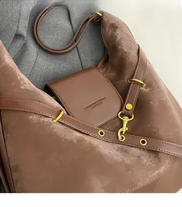 Close-up of textured dark brown leather tote with golden hooks and embossed logo