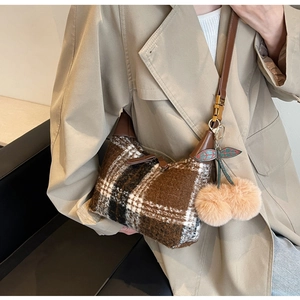 Detailed texture of autumn plaid wool handbag with luxury leather strap and cherry charm