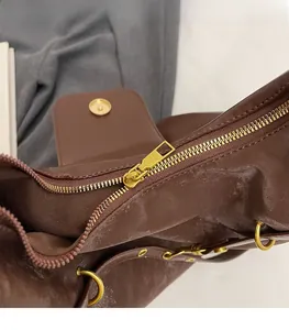 Close-up of golden hardware zipper and magnetic buckle on brown matte leather tote bag