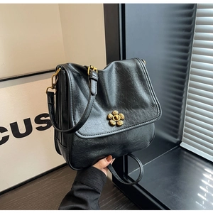 Detail of a black faux leather handbag featuring a vintage golden flower twist lock