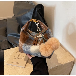 Close-up of retro plaid handbag with plush texture and decorative fur ball charm
