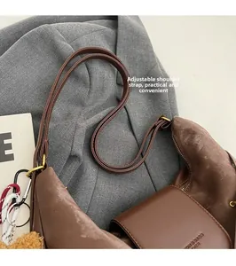 Detail of dark brown leather tote with adjustable shoulder strap and gold metal hardware