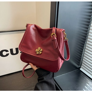 Close-up of a burgundy vintage shoulder bag with a gold flower buckle and soft leather texture