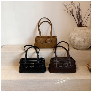 Three leather baguette shoulder bags in black, coffee, and tan colors on a stone stand