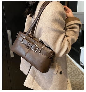 Detail of dark brown leather shoulder bag with silver buckle and belt design