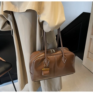 Detail of dark brown glossy Boston bag with mini pouch accessory on trench coat outfit