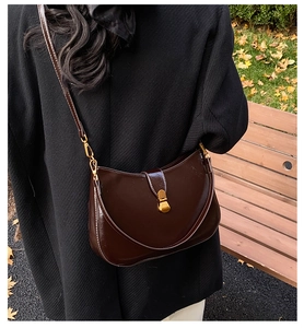 Detail of a vintage dark brown leather hobo bag with golden buckle in autumn street setting