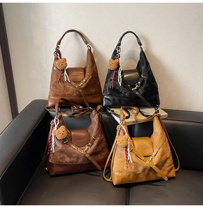 Detail of four suede tote bags in black, coffee, yellow, and brown with bear charms
