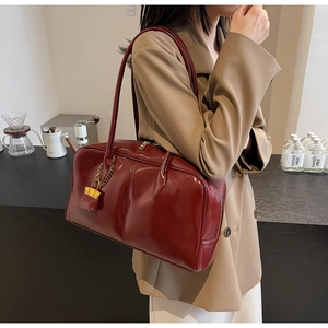 Close-up of wine red glossy PU leather shoulder bag with decorative mini padlock charm