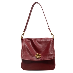 Retro burgundy faux leather crossbody bag with golden flower clasp on white background